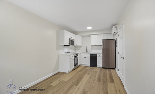 A kitchen with white cabinets and a wooden floor.